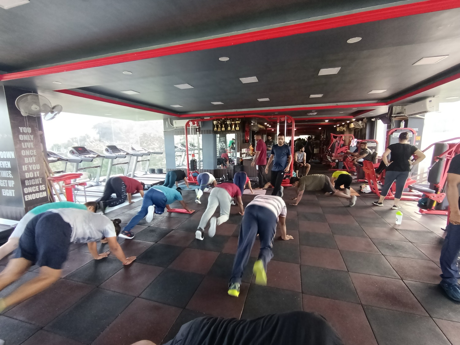 A group doing push-ups on the tiled floor in front of the treadmills