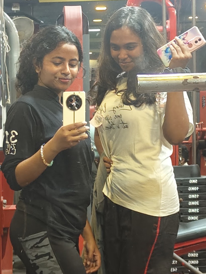 Two women taking a mirror photo beside the red racks